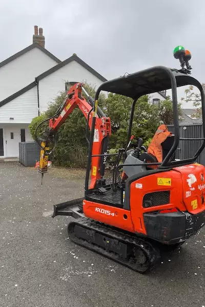Kubota KX015-4 mini-excavator on tarmac driveway for surface level excavation.