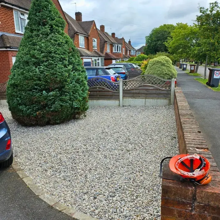 Driveway border with established conifer and decorative stone gravel covering the border space.